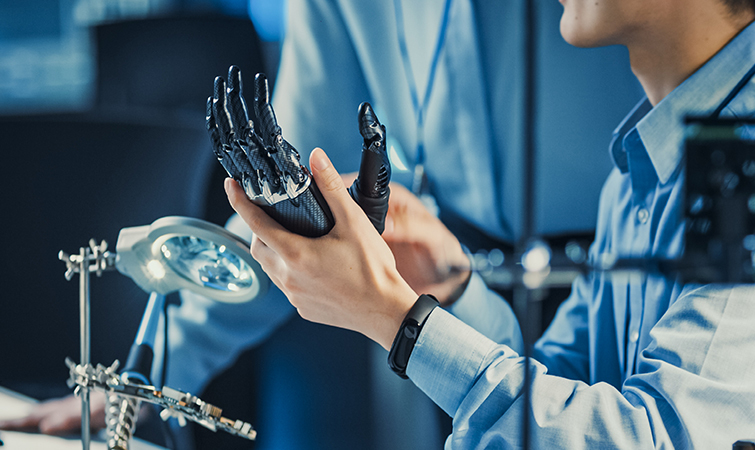 Engineering holding a model of a machine hand in a lab